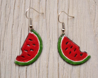 May include: A pair of watermelon slice earrings with silver hooks. The watermelon slices are red with black seeds and green rind.