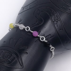 Könnte beinhalten: Ein silbernes Kettenarmband mit vier Perlen: gelb, weiß, rosa und schwarz.