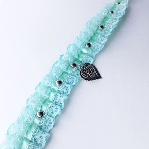May include: A light blue lace choker with a silver heart charm and silver studs.