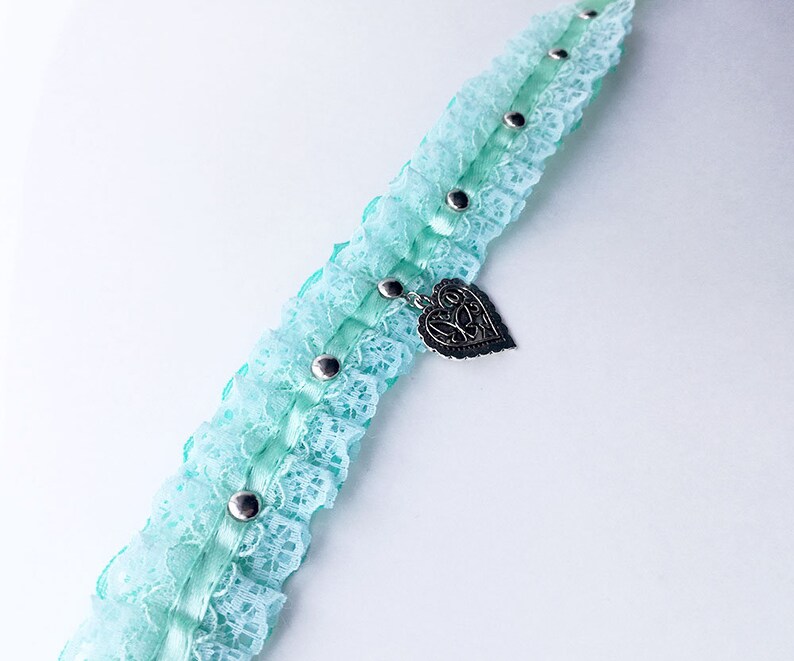 May include: A light blue lace choker with a silver heart charm and silver studs.