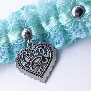 May include: A light blue lace garter with a silver heart charm featuring a butterfly design.
