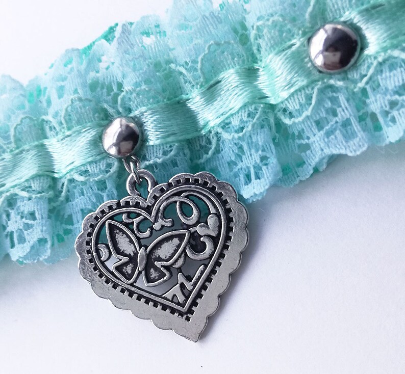 May include: A light blue lace garter with a silver heart charm featuring a butterfly design.
