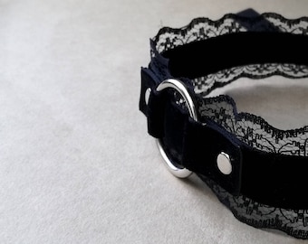 May include: Black velvet choker with a silver ring and black lace trim.