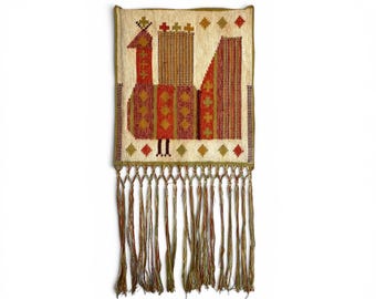 May include: A rectangular woven wall hanging featuring a stylized bird motif in shades of red, orange, and olive green on a cream background. The design includes geometric patterns and a long fringe of multi-colored threads along the bottom edge.