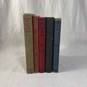 May include: A collection of five vintage books with worn covers. Titles include "First Year Algebra," "The Triangle-Arithmetics," and "Modern Junior Mathematics." The books are in various colors, including green, red, and blue.