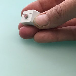 May include: A small white cube with a round, brown button on the top.