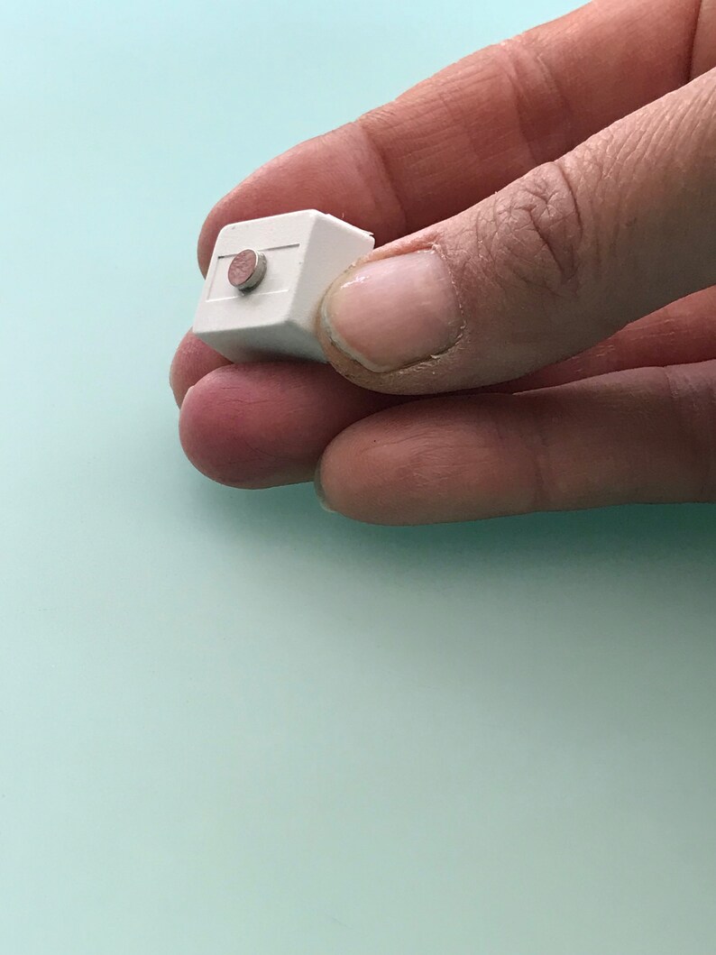 May include: A small white cube with a round, brown button on the top.