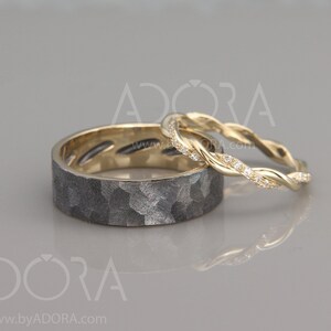 Op de afbeelding: Twee trouwringen, een met een gehammerde zwarte afwerking en de andere een gedraaide gouden ring met kleine diamanten.