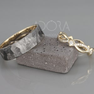 Pode incluir: Duas alian&ccedil;as de casamento, uma com acabamento martelado e a outra com um design delicado de diamantes. As alian&ccedil;as s&atilde;o de ouro e s&atilde;o exibidas em uma pedra cinza.