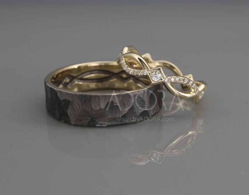 Pode incluir: Um par de alian&ccedil;as de casamento. A alian&ccedil;a &agrave; esquerda &eacute; feita de metal preto com uma textura martelada. A alian&ccedil;a &agrave; direita &eacute; feita de ouro amarelo com um delicado design de diamantes.