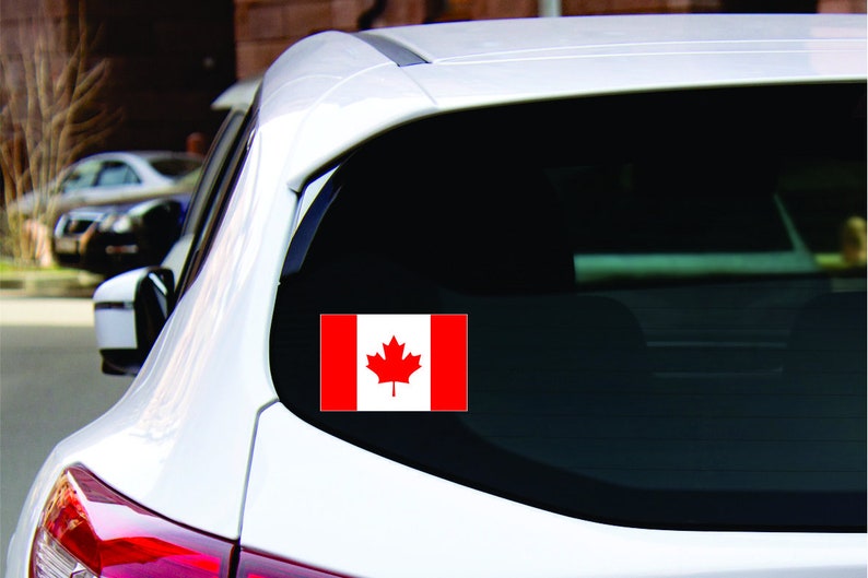 May include: A white car with a Canadian flag sticker on the back window. The flag is red and white with a red maple leaf in the center.