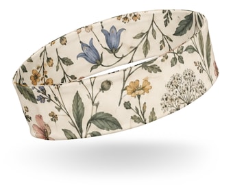 Può includere: Una fascia per capelli larga con sfondo bianco sporco e una stampa botanica di fiori blu a forma di campana, fiori gialli, grappoli di piccoli fiori bianchi e foglie verdi disposti in un motivo ripetitivo sulla superficie del tessuto.