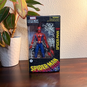 May include: A Marvel Legends Spider-Man action figure in its original packaging. The figure is in a classic red and blue costume, with a web design on the packaging. The box features the text "Spider-Man" and "Marvel Legends Series".