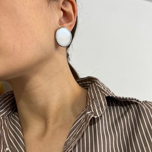 White enamel disc stud earrings worn by woman modern look