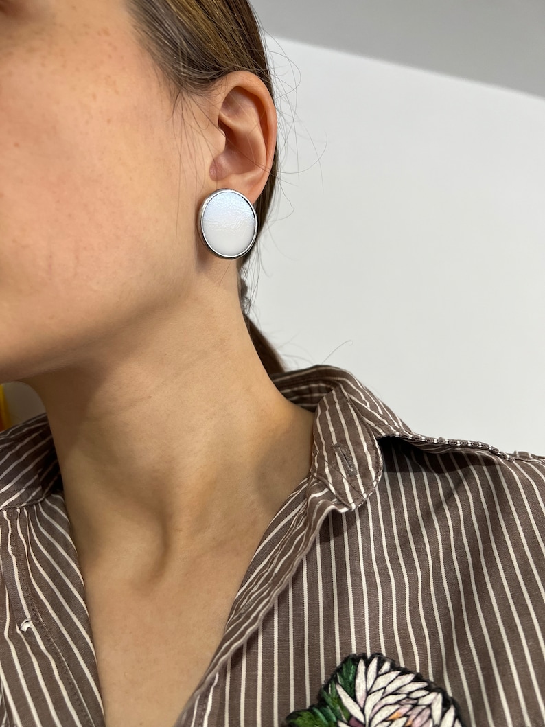 White enamel disc stud earrings worn by woman modern look