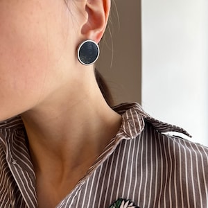 Close up black minimalist disc earrings silver tone setting