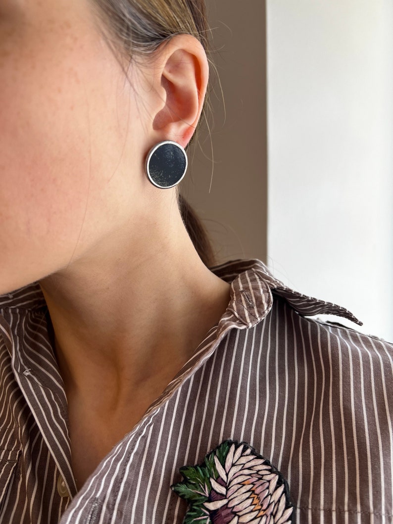 Close up black minimalist disc earrings silver tone setting