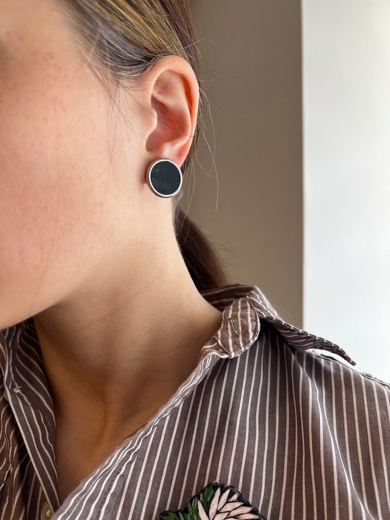 Large black stud earrings worn with striped shirt side view