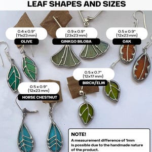 May include: Assortment of leaf-shaped earrings made of stained glass. Each earring is a different colour and shape, including green, blue, and orange. The earrings are labelled with their names and measurements in inches and millimetres. The text "NOTE! A measurement difference of 1mm is possible due to the handmade nature of the product." is at the bottom of the image.