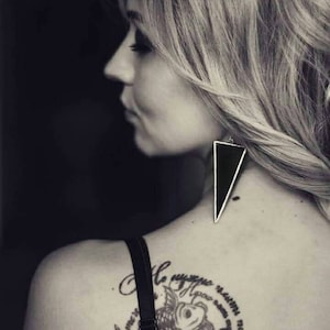May include: Black and white photo of a woman with a tattoo on her back. The tattoo is a circle with two fish inside and text in Russian. The text reads "Не ругай меня, мама, не махай рукой".