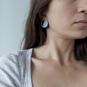 Side profile with modern black disc stud earrings silver frame