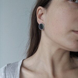 Black geometric round stud earrings on model minimal style