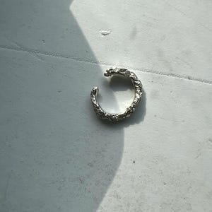 Delicado y fino pendiente tipo brazalete de plata de ley. Piercing falso tipo brazalete con textura fina.