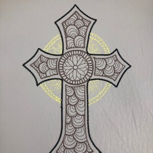 May include: A black and brown cross with a decorative design. The cross is outlined in black and has a brown mandala design in the center.