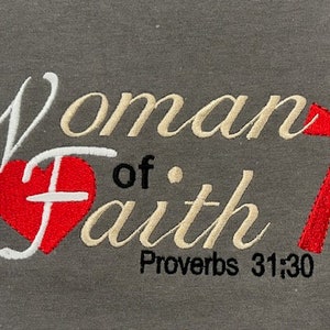 May include: A gray sweatshirt with the words "Woman of Faith" embroidered in white and gold. A red heart with a white cross is in the center of the words. A red cross is on the right side of the words. The words "Proverbs 31:30" are embroidered in black below the words.