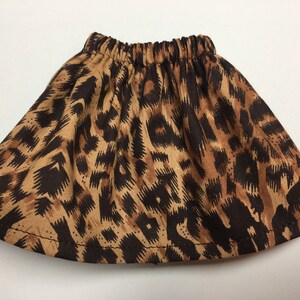 May include: A brown and tan leopard print skirt with an elastic waistband. The skirt is made of a lightweight fabric and has a flared silhouette. The animal print pattern is a classic design.