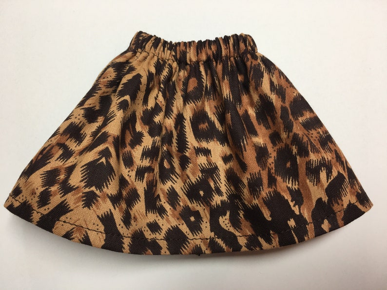 May include: A brown and tan leopard print skirt with an elastic waistband. The skirt is made of a lightweight fabric and has a flared silhouette. The animal print pattern is a classic design.