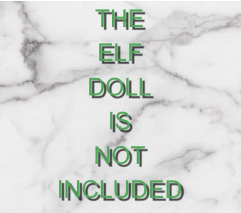 May include: White and gray marble background with green text that reads "THE ELF DOLL IS NOT INCLUDED". The text has a shadow effect, and the overall design is simple and direct.