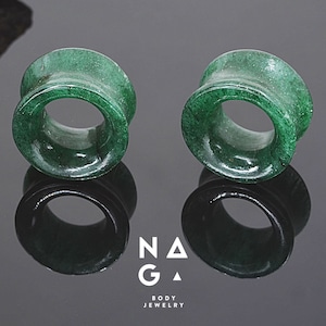 May include: Two green jade stone ear gauges, each with a circular opening. The gauges are smooth and polished.