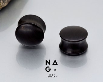 May include: Two black wooden ear gauges, one is round and the other is a flared style.