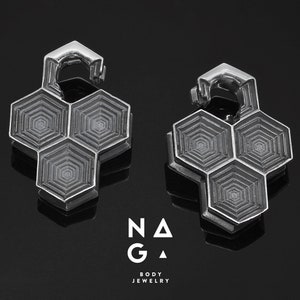 以下が含まれることがあります： ヒンジデザインのシルバーの六角形のイヤーカフのペア。カフは金属製で、幾何学模様が施されています。