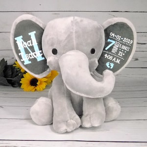 May include: Gray plush elephant baby toy with embroidered ears. One ear says "Noah Isaac" and the other ear says "04-01-2019 7 pounds 8 ounces 21" 4:08 A.M."