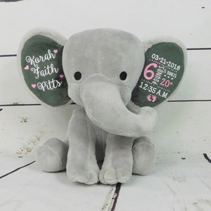 May include: Gray plush elephant stuffed animal with embroidered details. The elephant's ears are personalized with the name "Korah Faith Pitts", the date "03-21-2018", the time "12:35 A.M.", and the baby's weight and length: "6 pounds 20 inches".