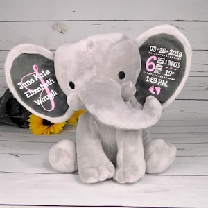 May include: Gray plush elephant stuffed animal with embroidered ears. One ear says "June Kate Elizabeth Waugh" and the other ear says "03-25-2019 6 pounds 3 ounces 19" 1:59 P.M."
