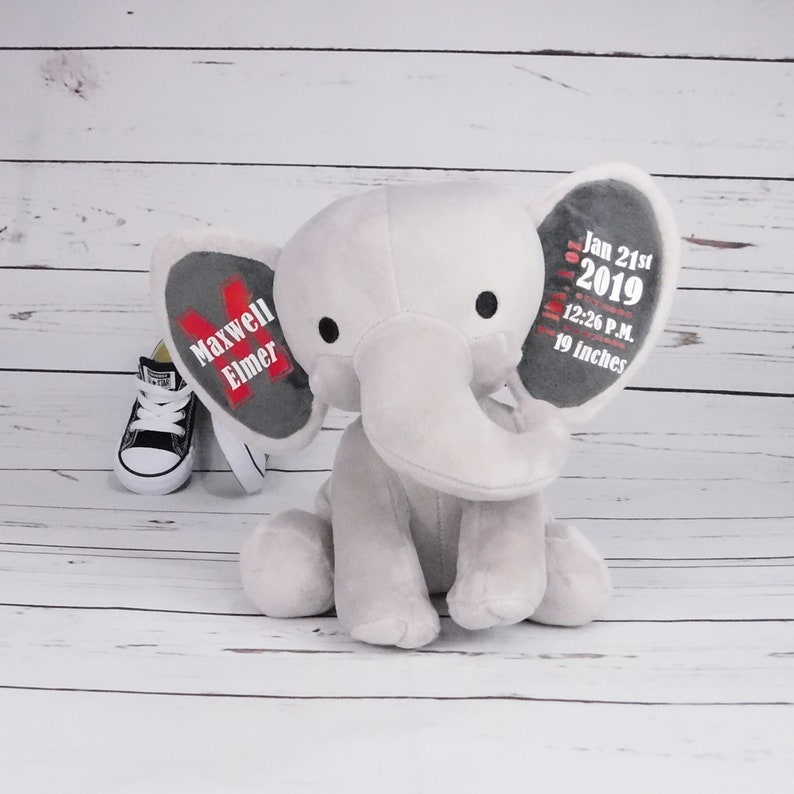 Puede incluir: Elefante de peluche gris con orejas bordadas. Una oreja dice "Maxwell Elmer" y la otra oreja dice "Jan 21st 2019 12:26 P.M. 19 inches".