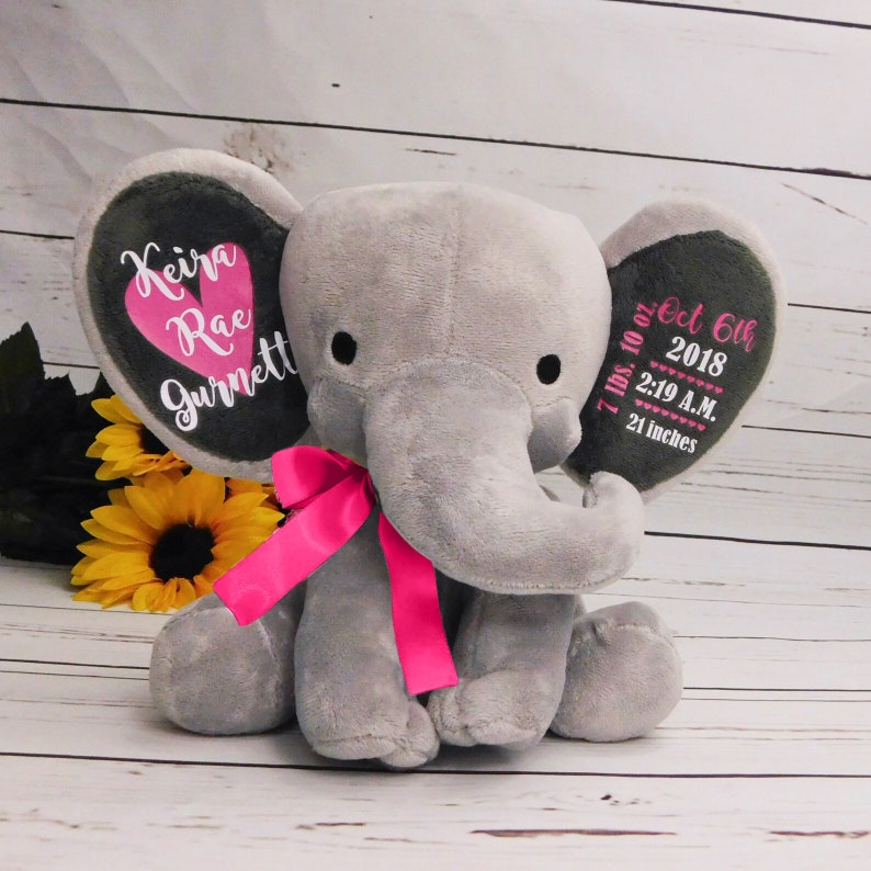 May include: Gray plush elephant with pink ribbon, personalized with the name "Keira Rae Gurnett" and birth details: 7 lbs. 10 oz., Oct 6th 2018, 2:19 A.M., 21 inches.