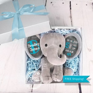 May include: A gray plush elephant toy in a white gift box with blue tissue paper. The elephant has two black felt eyes and a blue felt circle on each ear. One circle says "Bradley James" and the other says "09 06 2020 5 pounds 9 ounces 19" 6:50 A.M."