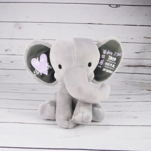 May include: Gray plush elephant with embroidered details. One ear has a pink heart with the names "Rylan Elizabeth" and the other ear has the date "Jan 23rd 2019", time "4:15 P.M." and measurements "5 lbs. 15 oz. 19 inches".