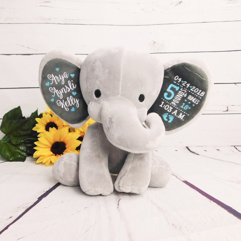 May include: A gray plush elephant with embroidered ears. One ear has the names "Arya Aynsli Kelly" and the other ear has the text "04-24-2018 5 pounds 6 ounces 18" 1:03 A.M."