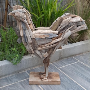 Puede incluir: Una escultura de gallo rústica de madera hecha de madera a la deriva. El gallo está de pie sobre una base de madera y tiene un diseño detallado.
