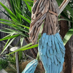 May include: A blue and brown driftwood mermaid sculpture. The mermaid's tail is made of driftwood painted blue, and the upper body is made of natural driftwood.