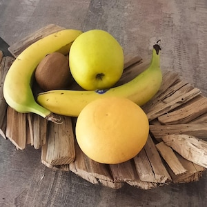 Peut inclure: Un plateau rustique en forme de feuille de bois présente un assortiment de fruits frais. L'arrangement comprend des bananes jaunes, un kiwi, une pomme jaune et une orange. Le plateau est en bois vieilli, ajoutant une esthétique naturelle.