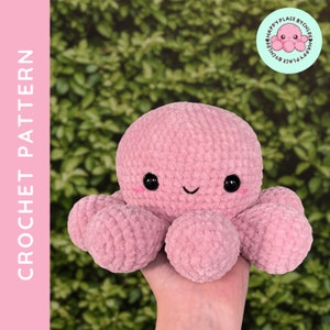 Puede incluir: Un pulpo de ganchillo rosa con ojos negros y una boca sonriente. El pulpo tiene ocho tentáculos redondeados y se sostiene en una mano. La imagen incluye el texto "CROCHET PATTERN" y un logotipo que dice "CHLOE HAPPY PLACE BY CHLOE HAPPY PLACE".