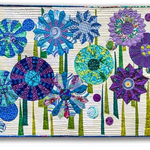 May include: A vibrant, handmade quilt with abstract floral designs in blue, green, and purple. The flowers have detailed petal patterns and are set against a cream background with vertical lines. The quilt has a blue border.