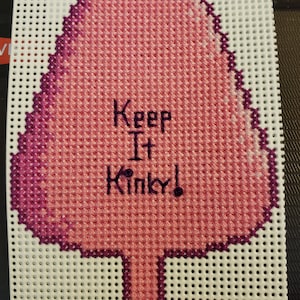 May include: Pink and purple cross-stitch embroidery of a tree with the text "Keep It Kinky!"