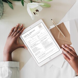 K&ouml;nnte beinhalten: Ein digitales Tablet mit einem Formular "Virtual Assistant Service Agreement". Das Dokument ist in Schwarzwei&szlig; gehalten und enth&auml;lt Abschnitte f&uuml;r Bedingungen, Serviceplan und Zubeh&ouml;r. Ein goldener Stift und ein brauner Umschlag sind ebenfalls zu sehen.